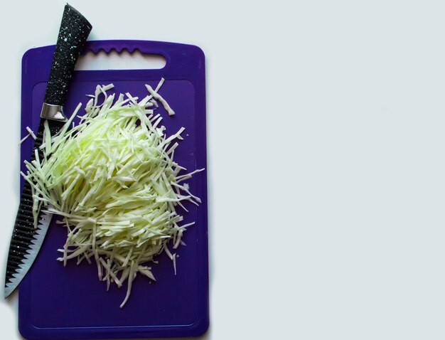 Zdjęcie na desce do krojenia warzywa nożem na białym tle
