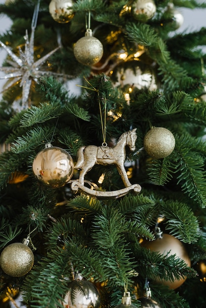 Na drzewie zawieszony jest świąteczny koń i kulki, ozdobione lampkami