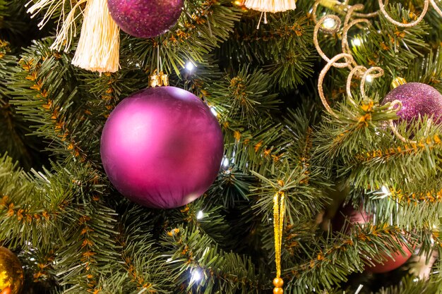 Na gałęzi zielonej choinki wisi świąteczna zabawka w kształcie różowej kuli na zielonym tle boże narodzenie w tle różowa piłka na gałęzi choinki