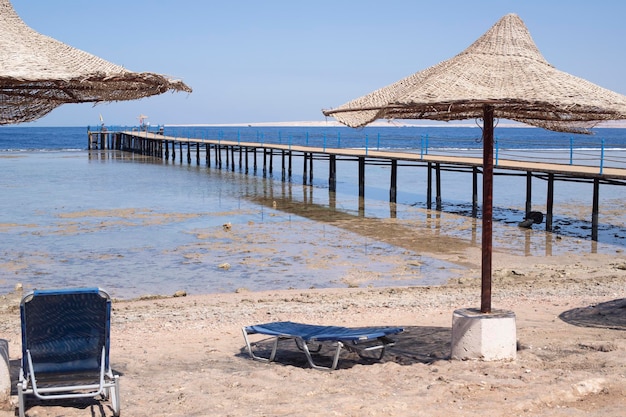 Na horyzoncie morze i plaża Parasole z leżakami i pontonem Wejście z plaży do wody