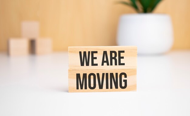 Na Jasnym Tle Drewniane Kostki I Drewniany Klocek Z Tekstem We Are Moving. Widok Z Góry