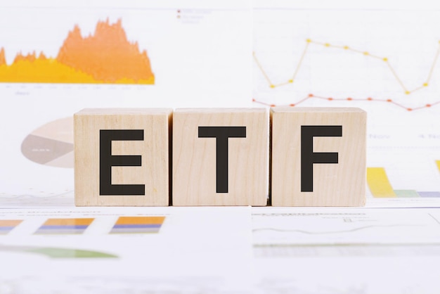 Na jasnym tle wykresy wykresy i drewniane kostki z napisem ETF Exchange Traded Fund