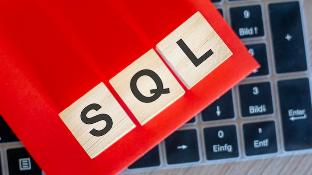 Na klawiaturze kostki notebooka z napisem SQL na czerwonym tle