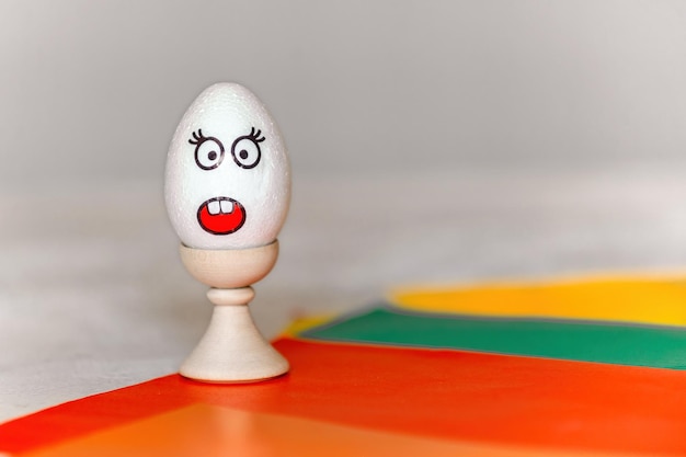 na kolorowym papierze stojak z jajkiem, na którym znajduje się naklejka z emocją zaskoczenia