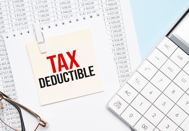 Na Notatniku Leżą żółta Kartka Z Napisem Tax Deductible Oraz Kalkulator.