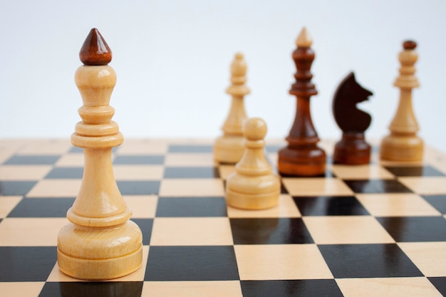 Na pierwszym planie na szachownicy znajduje się biały król za pozostałymi figurami szachowymi.