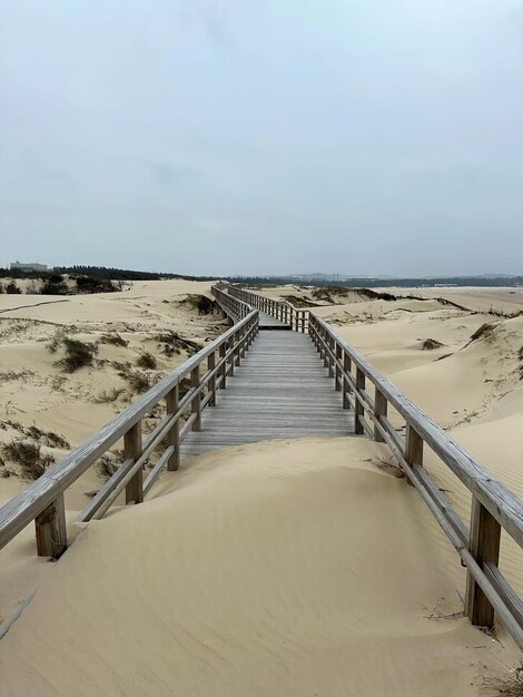 Na plażę prowadzi promenada, a piasek jest pokryty piaskiem.