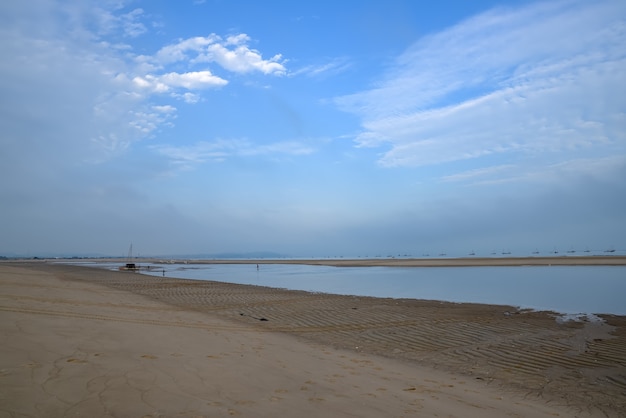 Na plaży nad morzem jest błękitne niebo i białe chmury