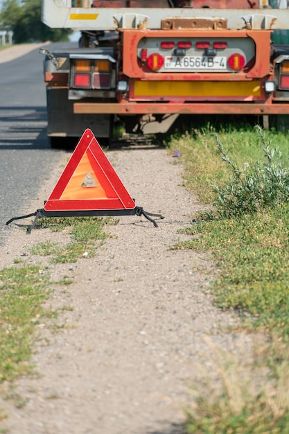 Na poboczu znajduje się czerwony znak stopu awaryjnego Wypadek na drodze z udziałem ciężarówki Transport ładunku i związane z nim zagrożenia w pracy