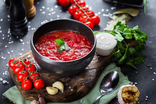 na półmisku Barszcz ukraiński z kapustą, z warzywami, pomidorkami cherry, sztućce na czarnym jest