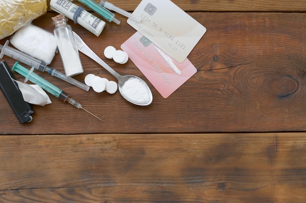 Na starym drewnianym stole leży wiele pigułek zawierających substancje odurzające i urządzeń do przygotowywania leków