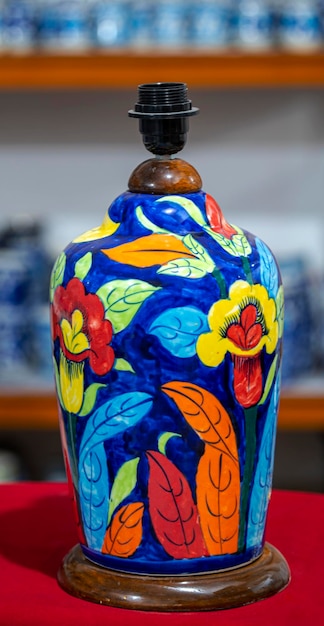 Na stole stoi kolorowy wazon z drewnianą rączką.