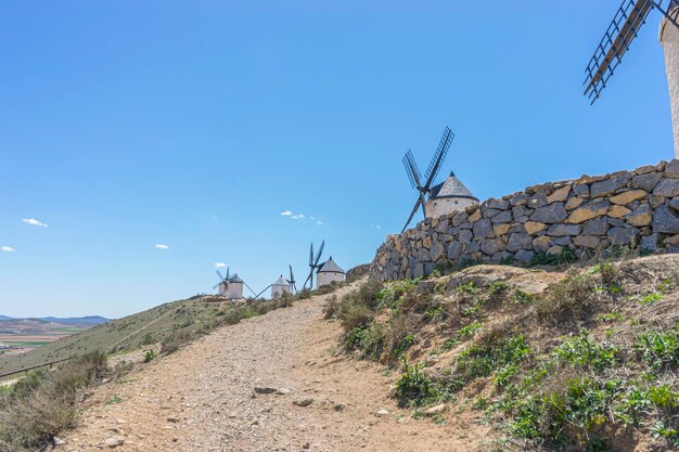 Zdjęcie na szczycie wzgórza widoczne są młyny wiatrowe na tle hiszpańskiego nieba.