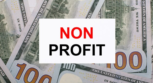 Na tle dolarów amerykańskich biała kartka z napisem NON PROFIT. Koncepcja finansowa