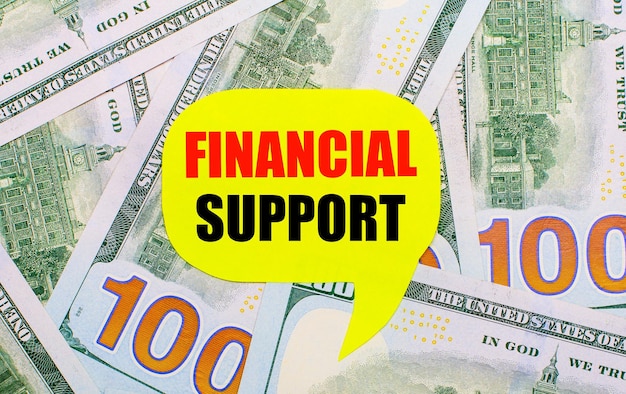 Na Tle Rozrzuconych Na Stole Dolarów Znajduje Się żółta Kręcona Kartka Z Tekstem Wsparcie Finansowe Koncepcja Finansowa