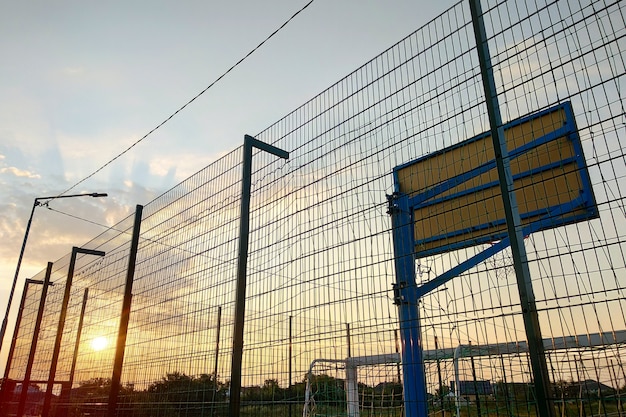 Na Zewnątrz Mini Boisko Do Piłki Nożnej I Koszykówki Z Bramką I Koszykiem Otoczone Wysokim Ogrodzeniem Ochronnym.