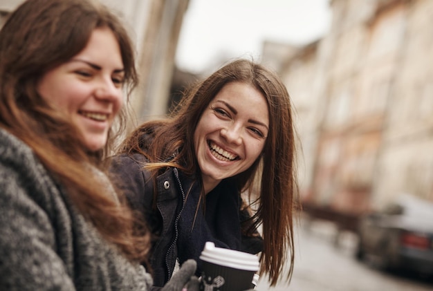 Na zewnątrz moda portret dwóch przyjaciół młodych pięknych kobiet picia kawy.