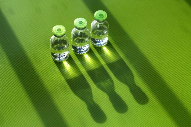 na zielonym stole stoją trzy ampułki z lekami z zastrzykiem