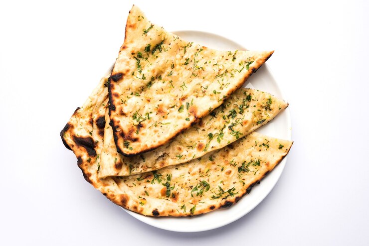 Zdjęcie naan z czosnkiem i kolendrą podany w talerzu, to rodzaj indyjskiego chleba lub roti z dodatkiem lahsun