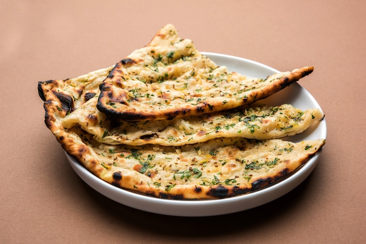 Zdjęcie naan z czosnkiem i kolendrą podany w talerzu, to rodzaj indyjskiego chleba lub roti z dodatkiem lahsun