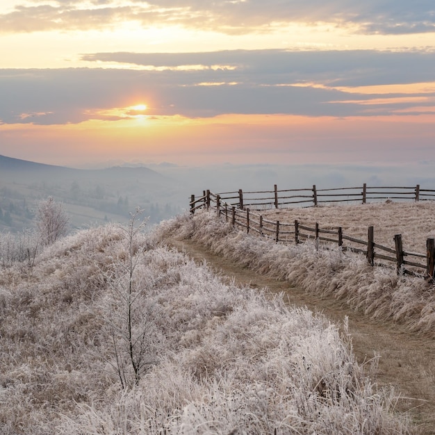 Nadchodzi zima Ostatnie dni jesiennego poranka w górskich krajobrazach spokojna malownicza szronowa scena Brudna droga ze wzgórz do wioski Ukraina Karpaty