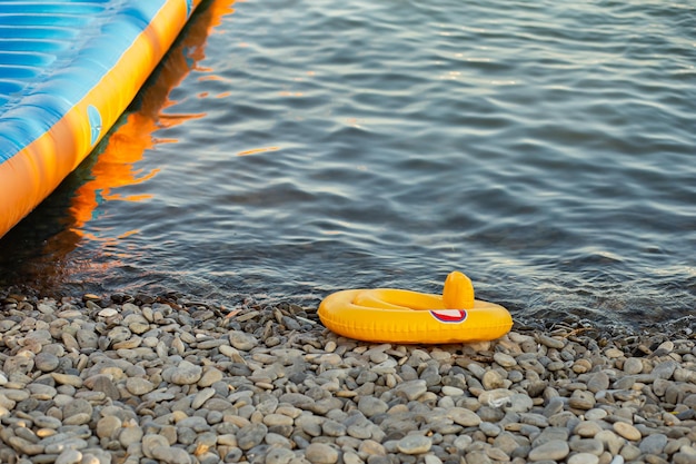 Nadmuchiwane żółte kółko dla dzieci na kamienistej plaży na tle morza