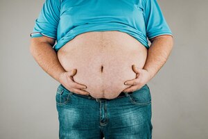 Zdjęcie nadwaga ciała z dłońmi dotykającymi brzucha pojęcie otyłości