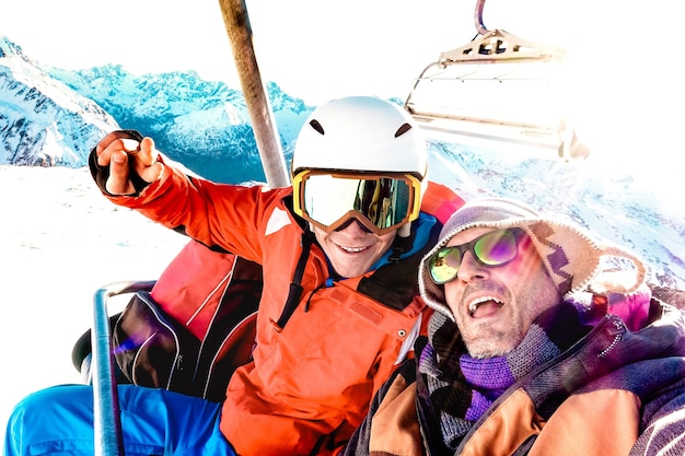 Najlepsi Przyjaciele Bawią Się Robiąc Selfie Na Wyciągu Krzesełkowym Ze Sprzętem Snowboardowym W Górskim Ośrodku Narciarskim