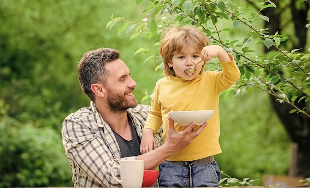 Najlepszy dzień w historii Zdrowa żywność i dieta Produkty mleczne Szczęśliwy dzień ojca Mały chłopiec z tatą jedzą płatki zbożowe Ojciec i syn jedzą obiad rodzinny na świeżym powietrzu Poranne śniadanie Dieta wegetariańska