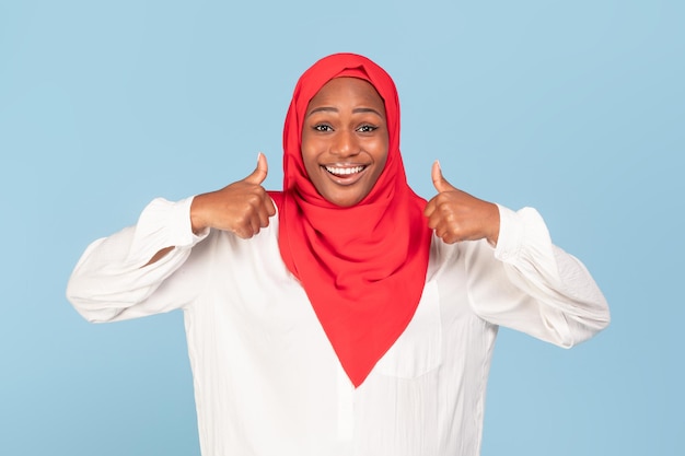 Najlepszy wybór Szczęśliwa czarna muzułmańska kobieta pokazuje kciuk w górę obiema rękami, polecając coś dobrego