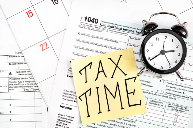 Naklejka ze słowami Czas podatkowy i zegar na formularzu podatkowym Koncepcja biznesowa