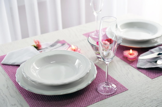 Nakrycie stołu dla dwóch osób z naczyniami i sztućcami na różowej serwetce