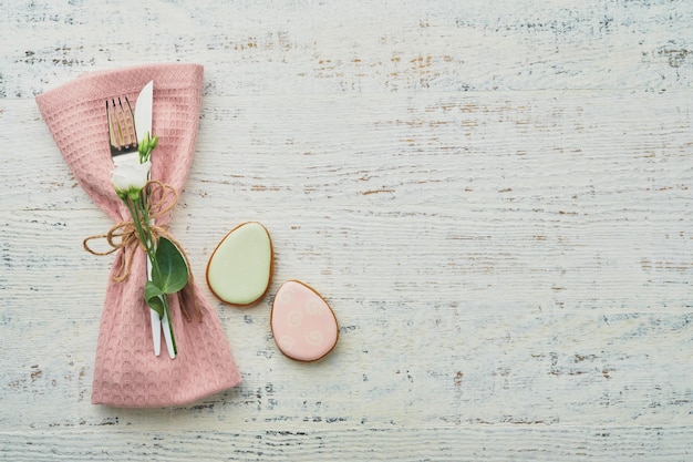 Nakrycie stołu wielkanocnego brunch Wiosenna koncepcja świąt wielkanocnych z białym różowym talerzem i serwetką z dekoracyjnymi symbolami wakacyjnych jajek królika i bukietem kwiatów na starym drewnianym tle Widok z góry