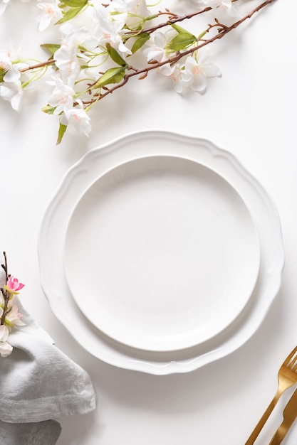 Nakrycie stołu wielkanocnego z kwitnącymi kwiatami na białym stole.