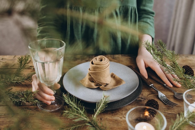 Zdjęcie nakrycie stołu z ceramicznymi talerzami, sztućcami i lnianą serwetką składaną w kształt róży