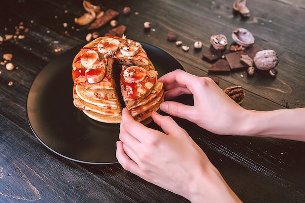 Naleśnik z pastą czekoladowo-orzechową, orzechami włoskimi i bananem na czarnym talerzu