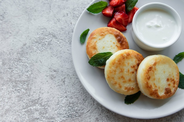 Naleśniki twarogowe ricotta na talerzu ceramicznym ze świeżą truskawką