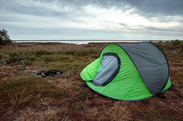 Namiot kempingowy zielony w tle przyrody i jeziora. podróże, turystyka, camping.