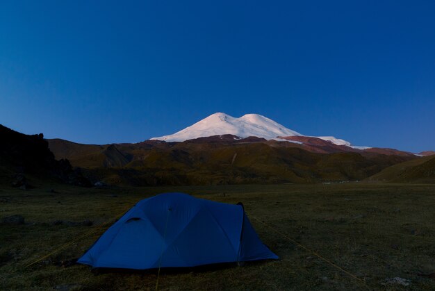 Namiot turystyczny na tle zaśnieżonych szczytów Elbrus w Rosji