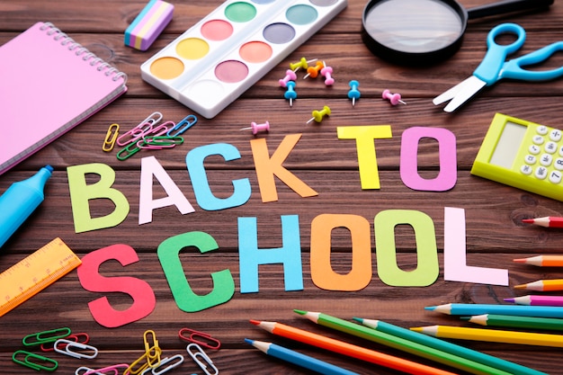 Napis Back To School z przyborów szkolnych na brązowej powierzchni drewnianej