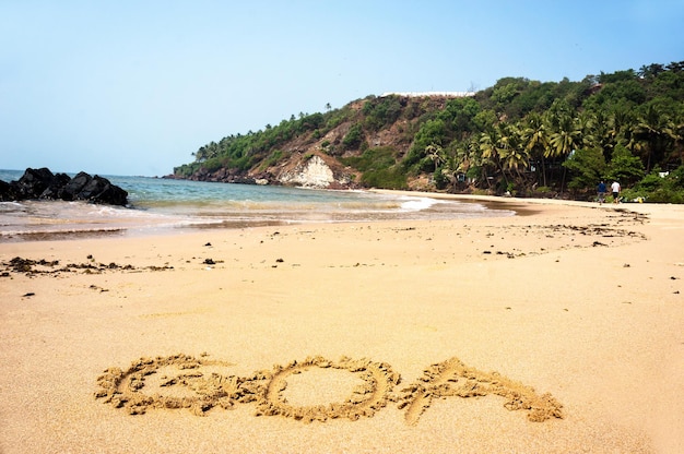 Napis Goa na piasku na plaży na tle błękitnego morza