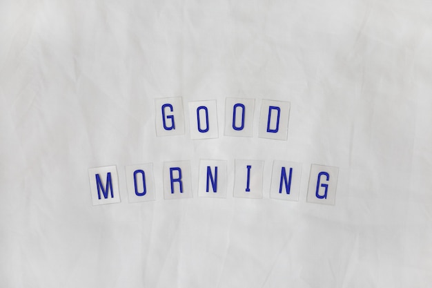Napis Good morning, złożony z granatowych liter na przezroczystych plastikowych podstawkach na białym tle