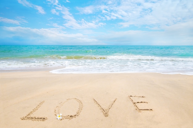 Napis Love napisany na piaszczystej plaży z fal oceanu