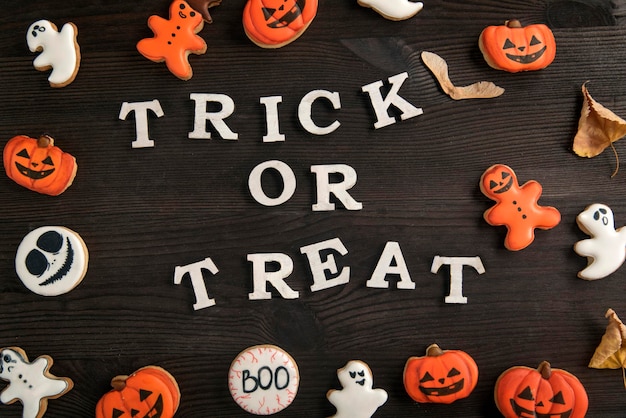 Napis trick or treat Halloween makieta białe i pomarańczowe pyszne imbirowe ciasteczka na brązowej drewnianej powierzchni