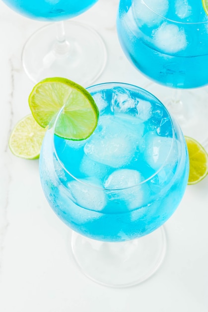 Zdjęcie napój alkoholowy szklanki z niebieskim koktajlem alkoholowym z dodatkiem lodu i limonki. blue curacao. trunek.