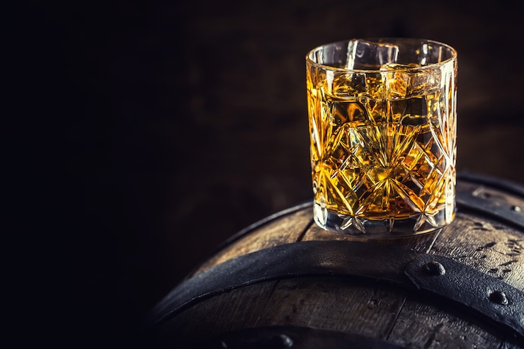 Zdjęcie napój whisky. kieliszek whisky na starej drewnianej beczce.