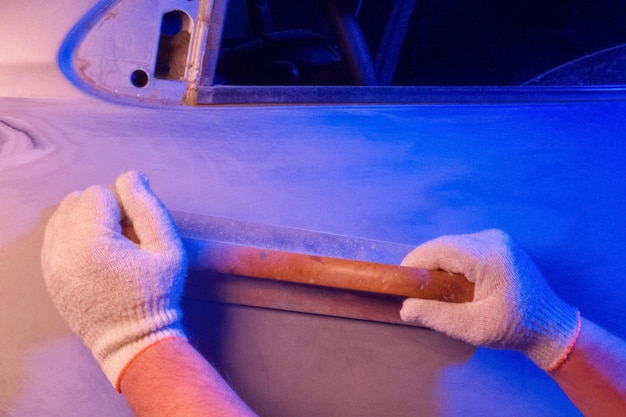 Zdjęcie naprawa karoserii szlifowanie części narzędziem ręcznym w warunkach garażowych abstrakcyjne niebieskie oświetlenie
