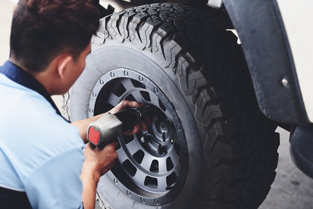 Naprawa lub zmiana mechanika pickup opon samochodowych przykręcanie odkręcania koła samochodu w serwisie naprawczym
