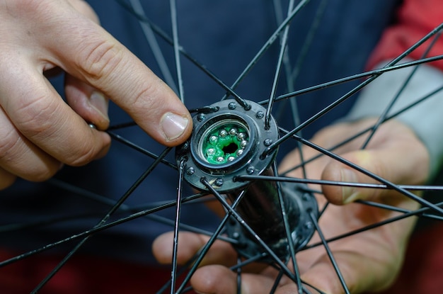 Zdjęcie naprawa rowerów wymiana smarowania i czyszczenie łożysk piast rowerowych nowe lśniące łożyska zamontowane w piaście tekstura skóry z bliska pracowite dłonie