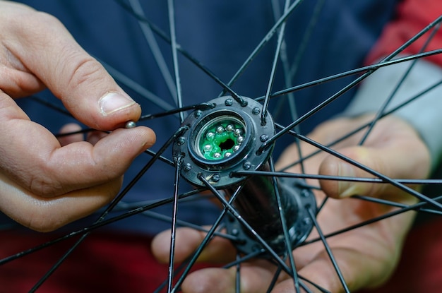 Zdjęcie naprawa rowerów wymiana smarowania i czyszczenie łożysk piast rowerowych w rękach mistrza nowe błyszczące łożyska pracowite dłonie zbliżenie